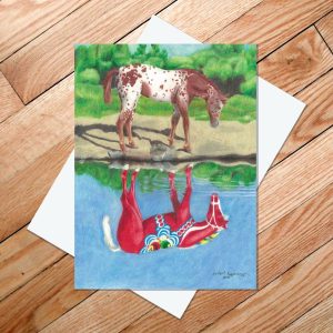 Greeting card of a strawberry roan appaloosa looking at its reflection of a red Dala horse