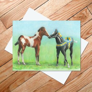 Greeting card of a bay pinto foal meeting a black Dala horse