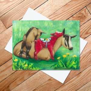 Greeting card of an Oberhasli goat with two kids, one which is red and inspired by the Swedish Dala Horse