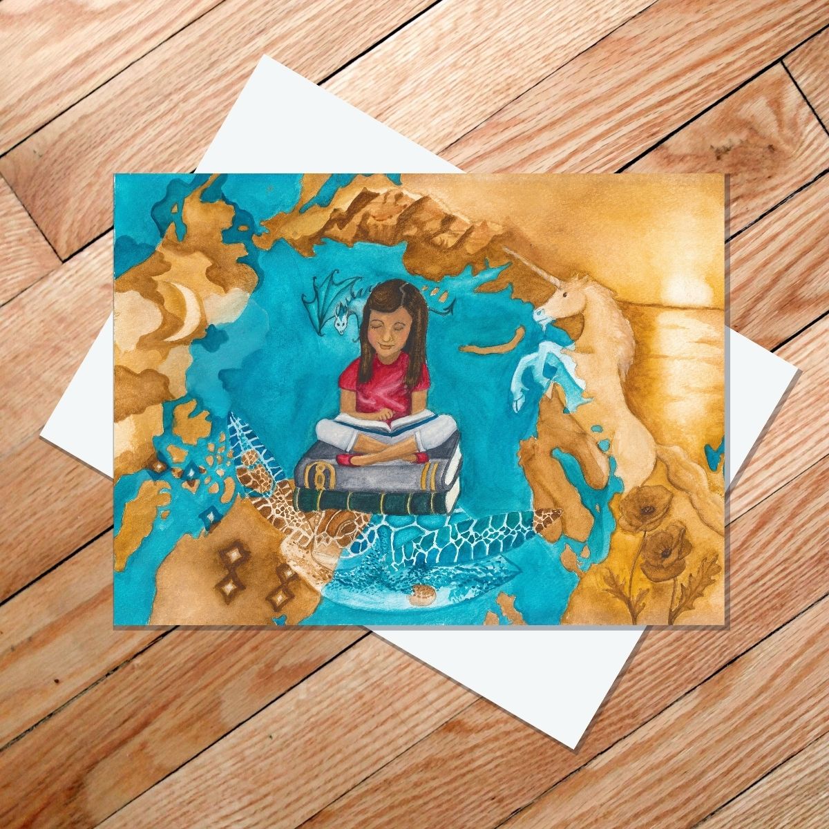 Greeting card of a girl sitting on a stack of books with images from stories surrounding her, including a sea turtle, unicorn, dragon, stars, mountains, and sunset