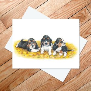 Greeting card of three basset hound puppies in autumn leaves